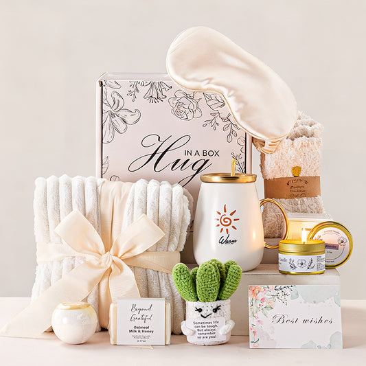 Gifting set with blanket, mug, candle, and small plant on a neutral background