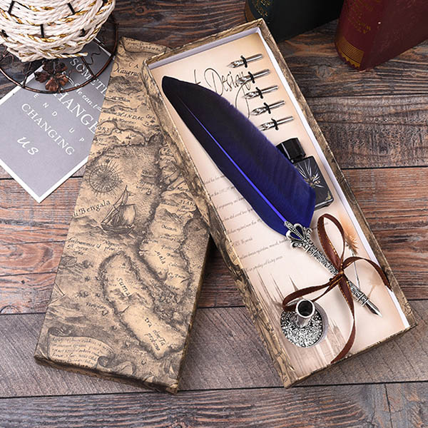 Feather quill pen set with ink bottle and accessories on a wooden surface