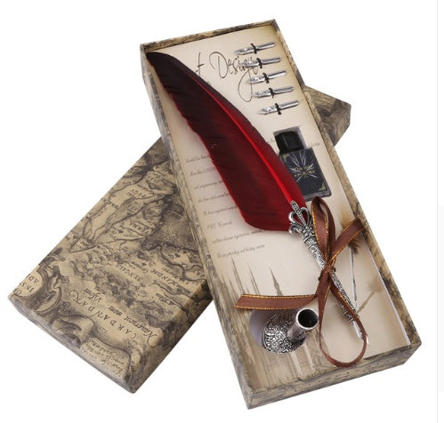 Feather quill pen set with ink bottle in a decorative box on a white background