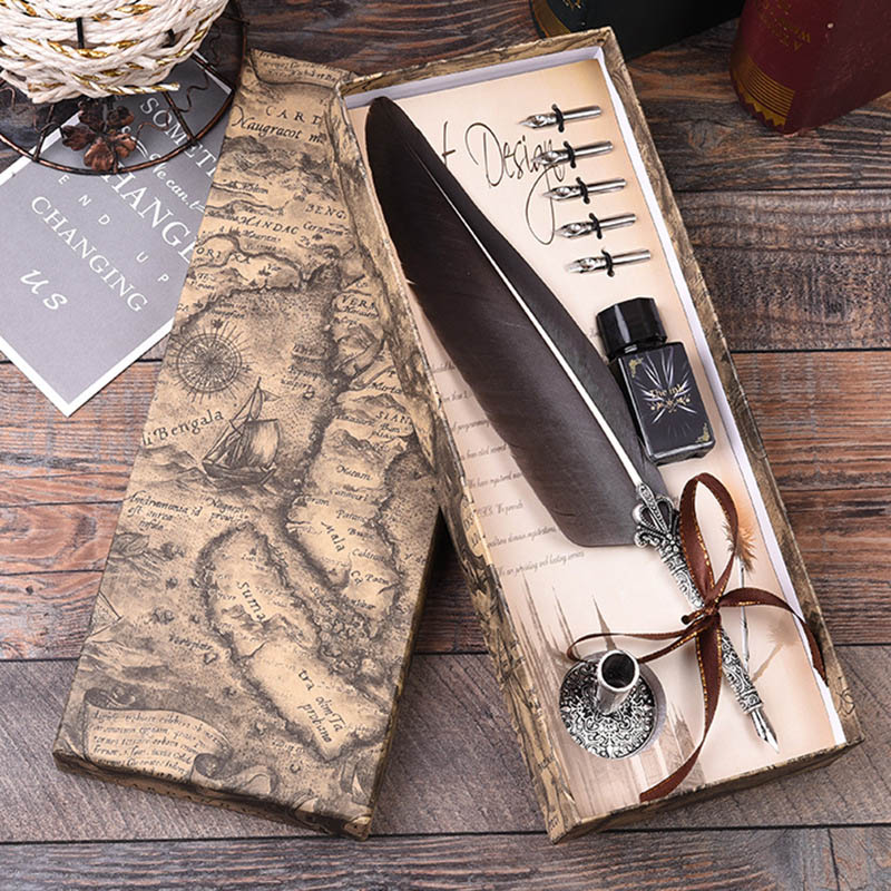 Feather quill pen set with ink bottle in a decorative box on a wooden surface
