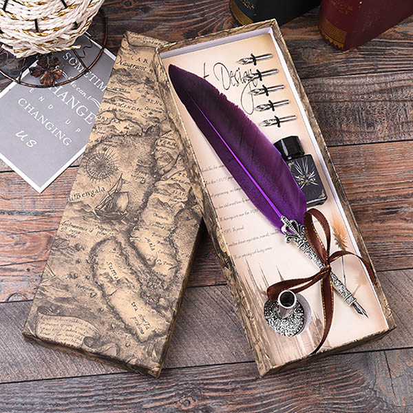 Feather pen set with ink bottle in a decorative box on a wooden surface