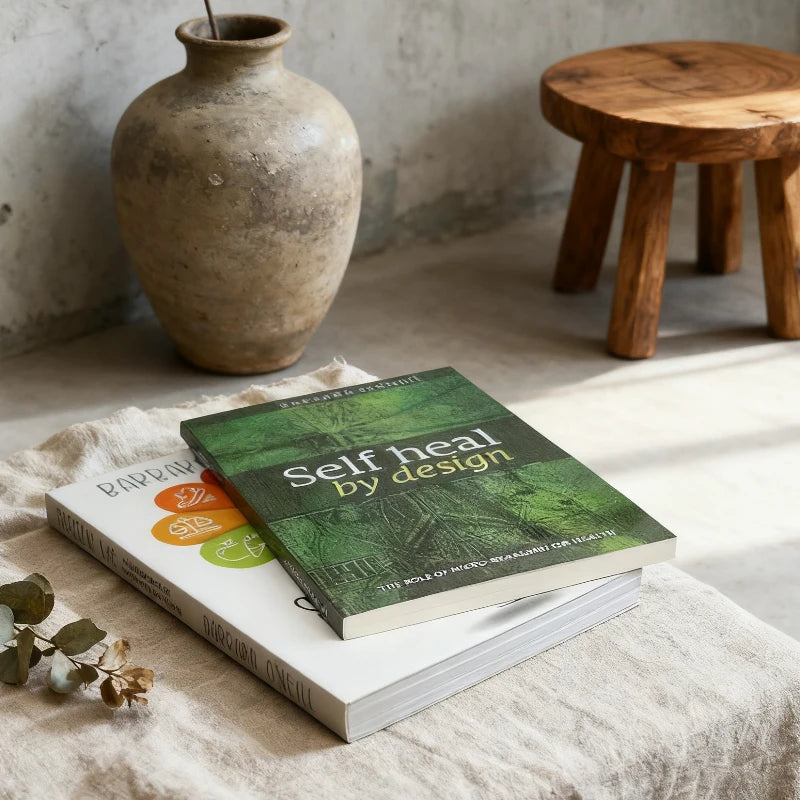 Book titled 'Self Heal by Design' on a surface with a vase and stool in the background