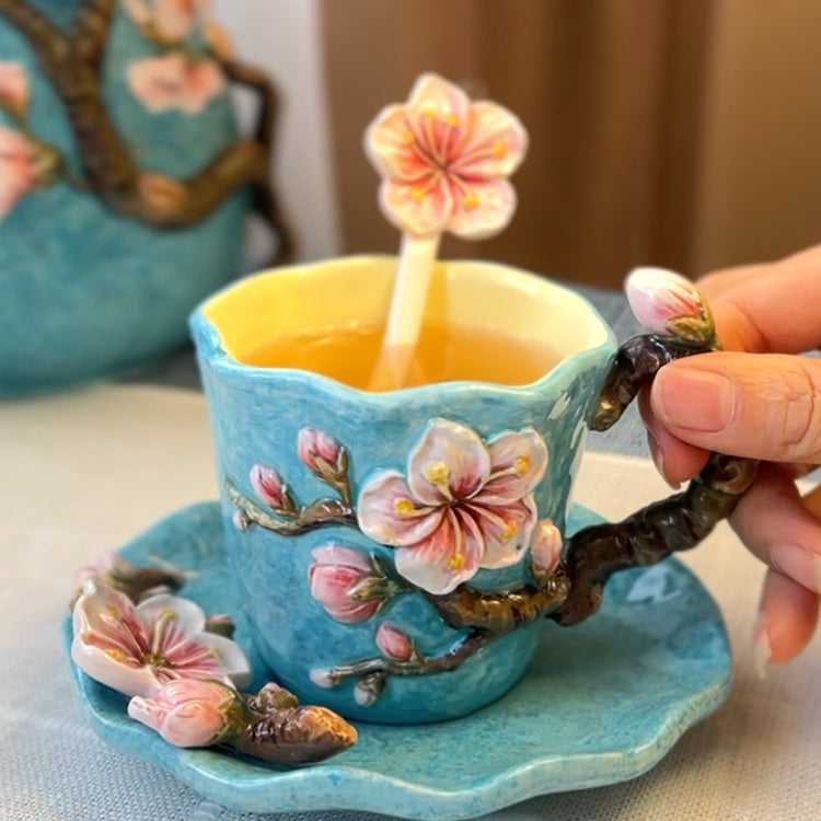 Decorative teacup with cherry blossom design held by a hand