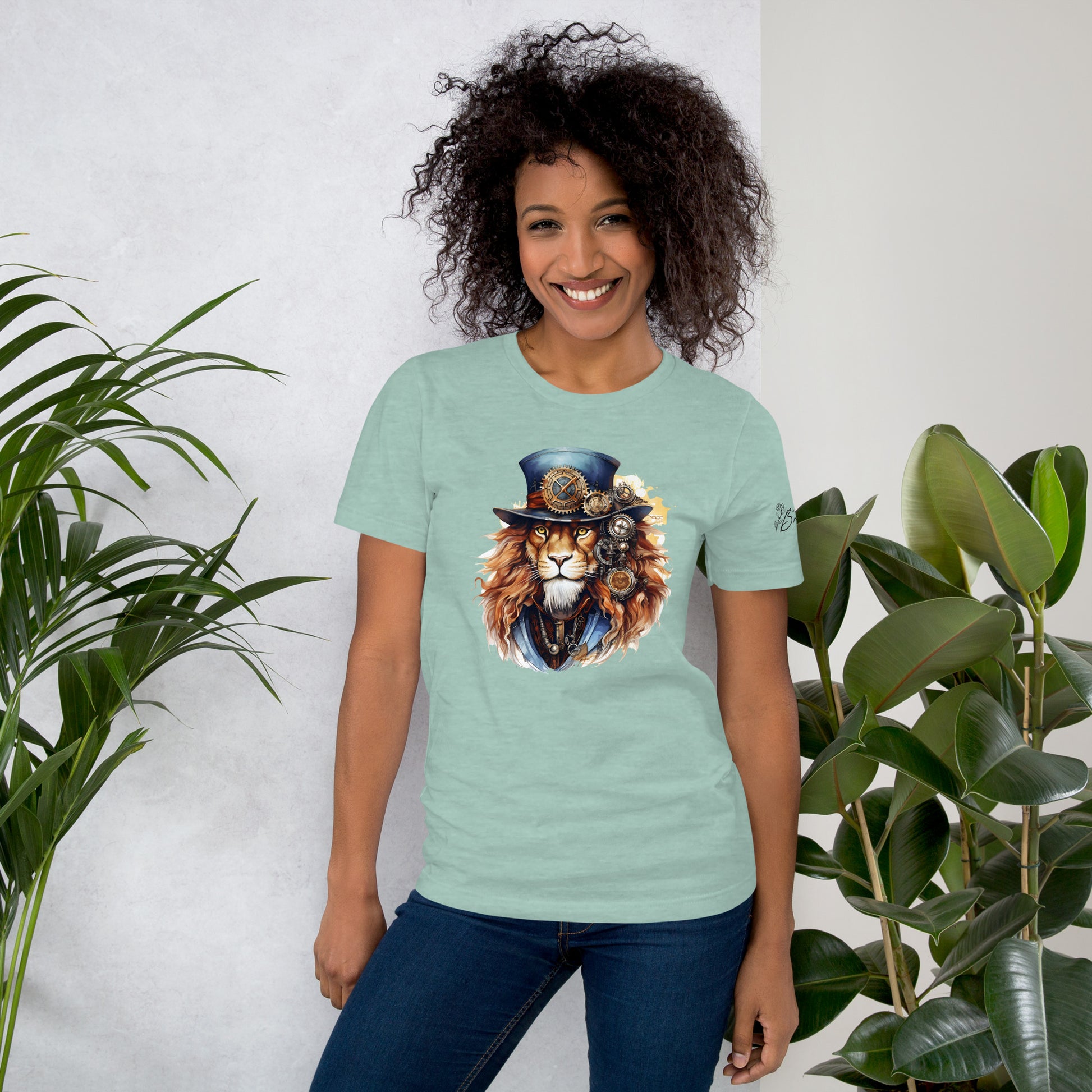 Woman wearing a light blue t-shirt with a lion graphic, standing between two plants against a white wall.