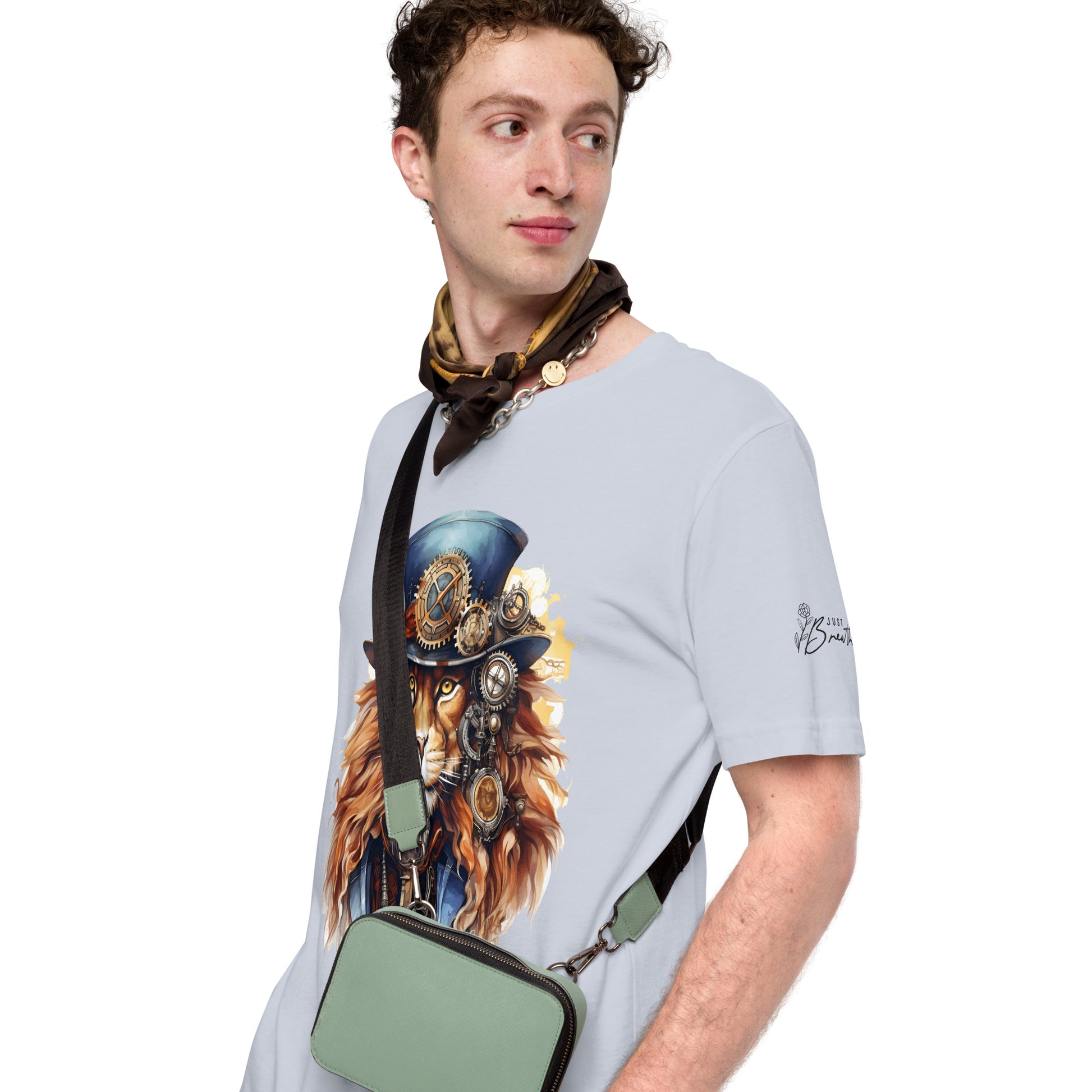 Man wearing a light gray t-shirt with a graphic design of a lion in a top hat and goggles, holding a green bag.